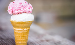 Cone of coconut and strawberry ice-cream on wooden background